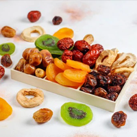 Assorted dried fruits in a wooden box on a white surface
